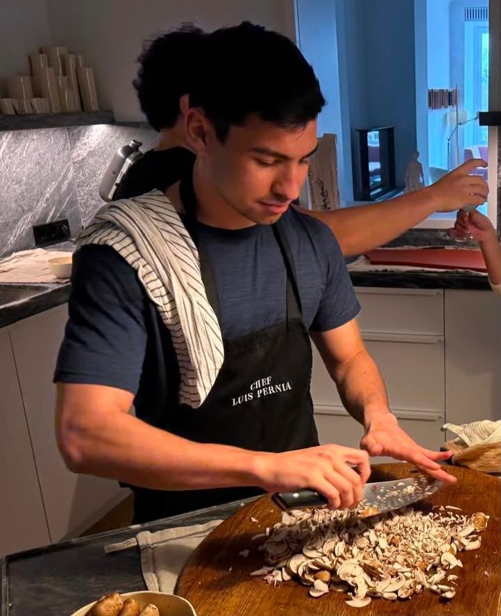 Luis Pernia slicing mushrooms in a home kitchen, wearing a Chef Luis Pernia apron