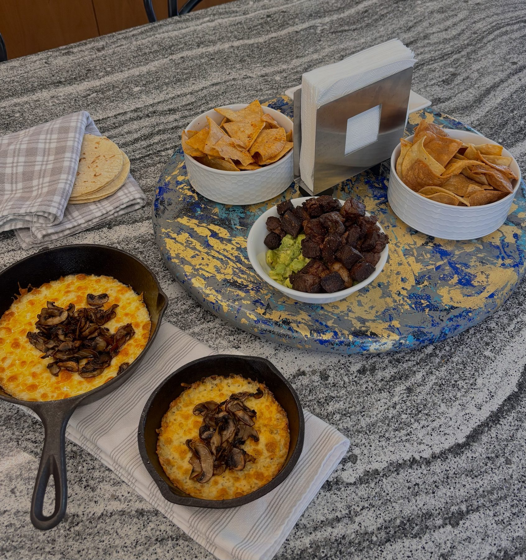 Queso fundido with mushrooms in cast-iron skillets, ribeye chicharrón over guacamole, totopos and tortillas